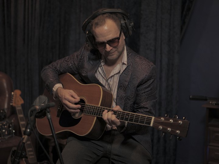 Adam Sandahl, known as ADAMORE, playing acoustic guitar in a recording session