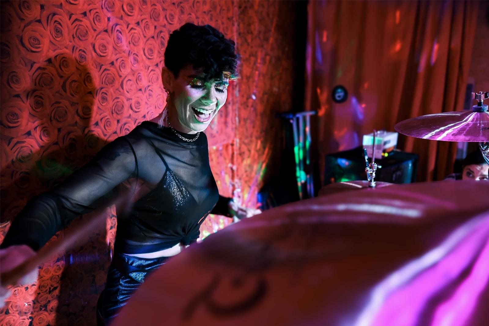 Natasha Caldas de Oliveira smiling while playing a drum kit